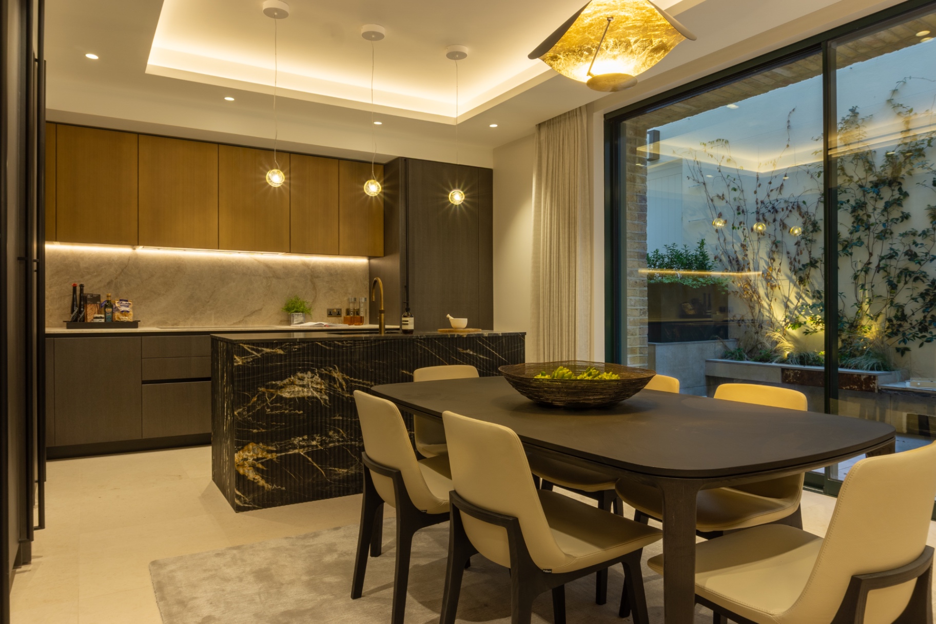 Kitchen and dining room opening onto a lit courtyard