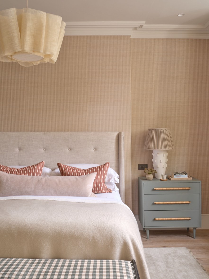 Principal bedroom with linen headboard, rattan-handled chest of drawers and rattan pendant
