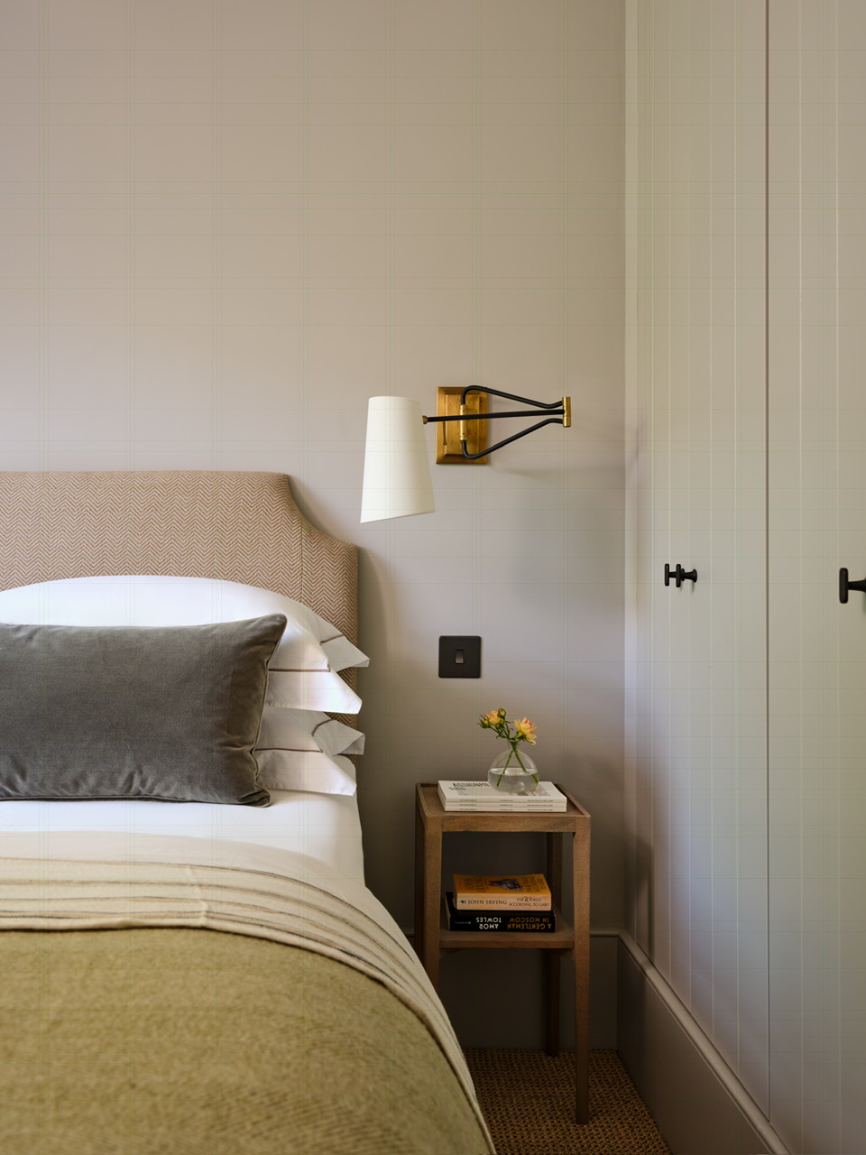 Bedroom detail with brass wall light and upholstered headboard