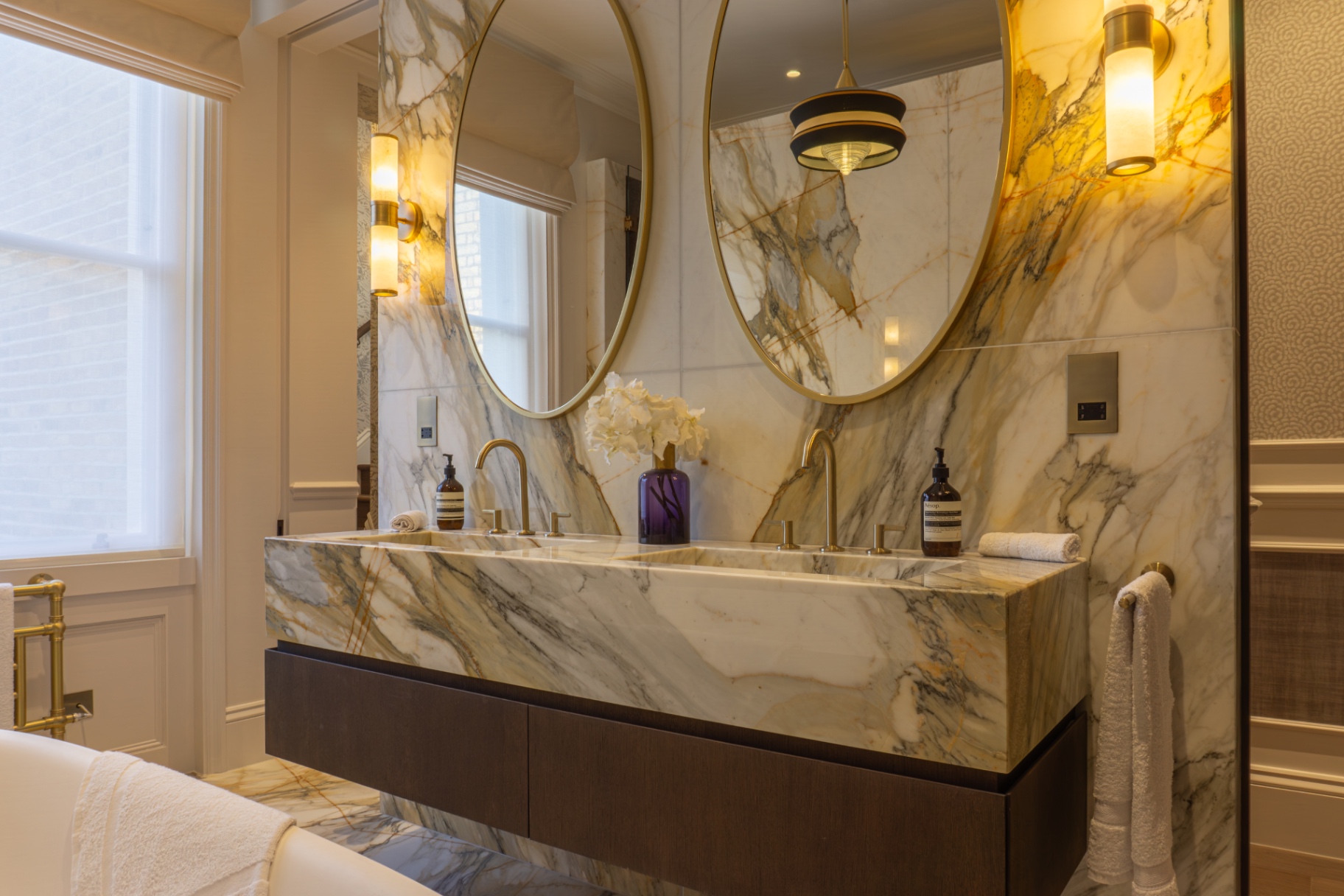 Marble double vanity with brass mirrors and wall lights