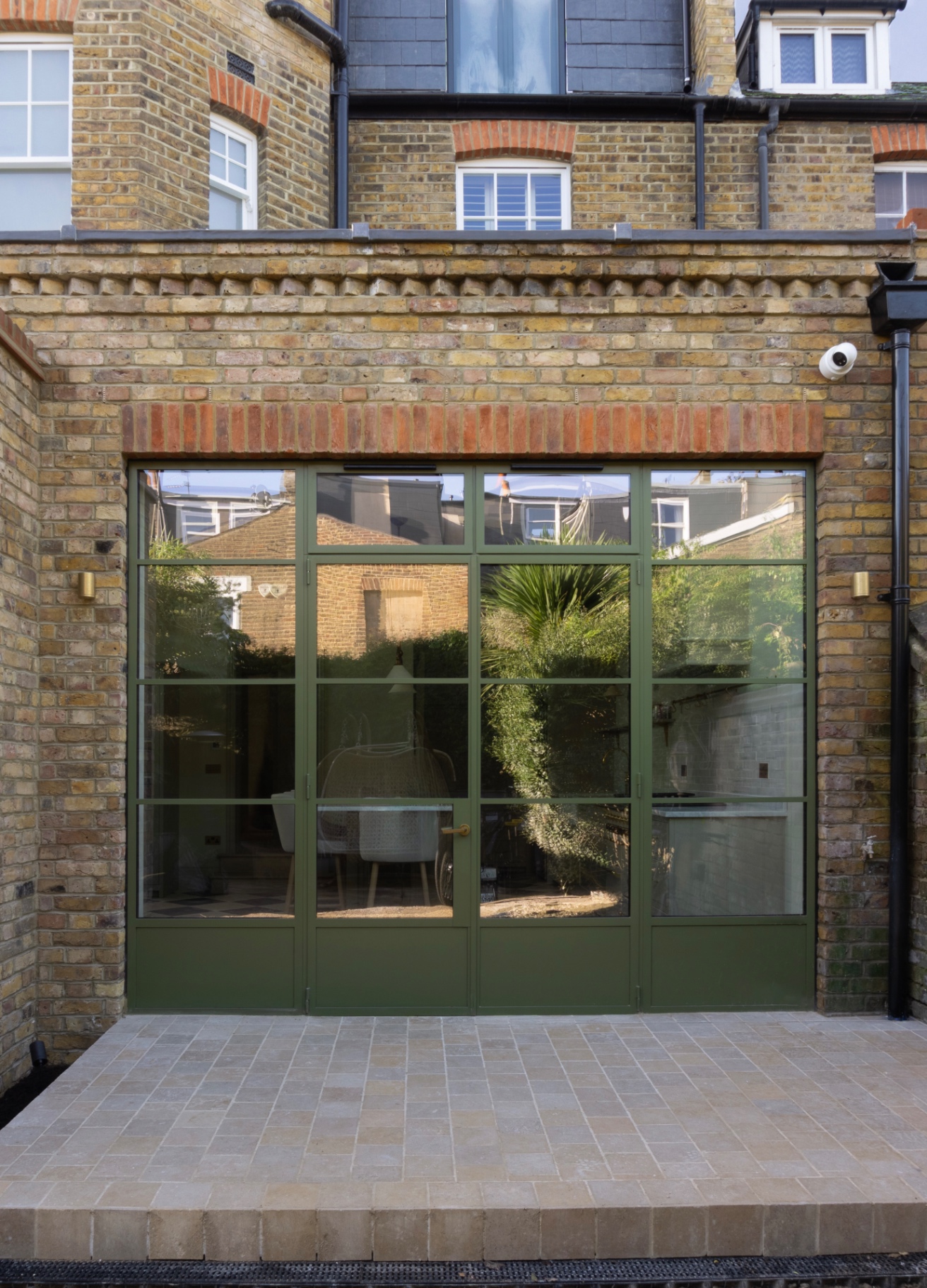 Rear extension exterior with green-framed glazed doors and paved terrace